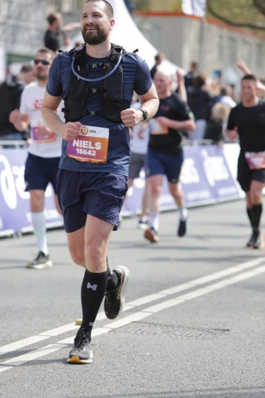Rotterdam Marathon 2025 Man in sportkleding loopt een marathon, omringd door andere hardlopers.